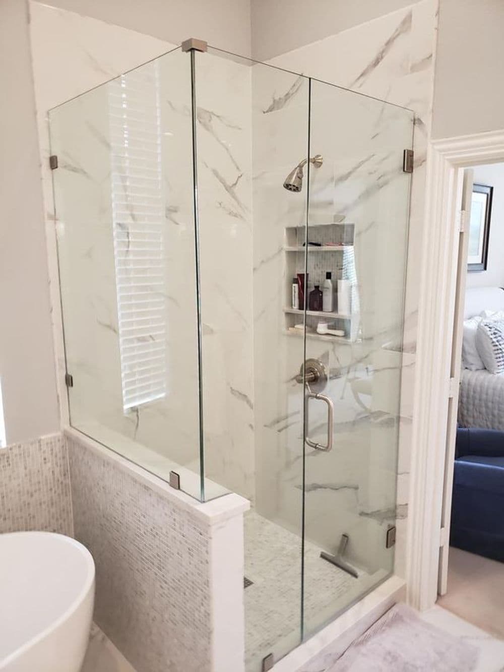 Modern glass shower enclosure with marble walls and stylish fixture in a clean bathroom setting.
