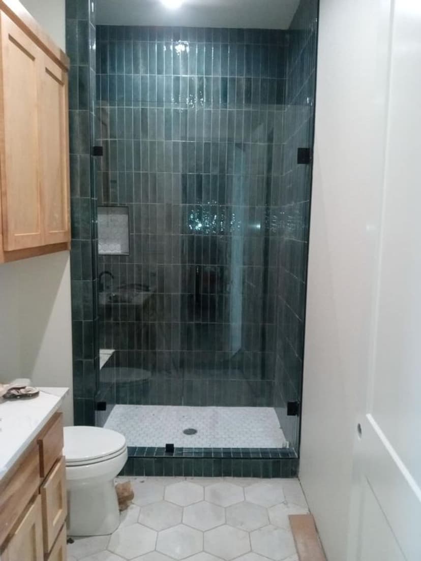 Modern bathroom featuring a glass shower, hexagonal tile flooring, and wooden cabinetry.
