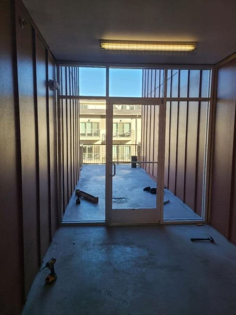 View of a hallway leading to an exterior door with natural light and construction tools.