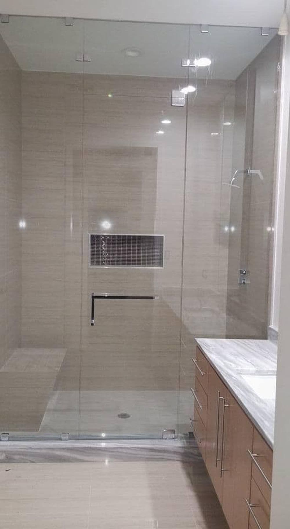 Modern bathroom featuring a spacious glass shower and sleek wooden vanity.