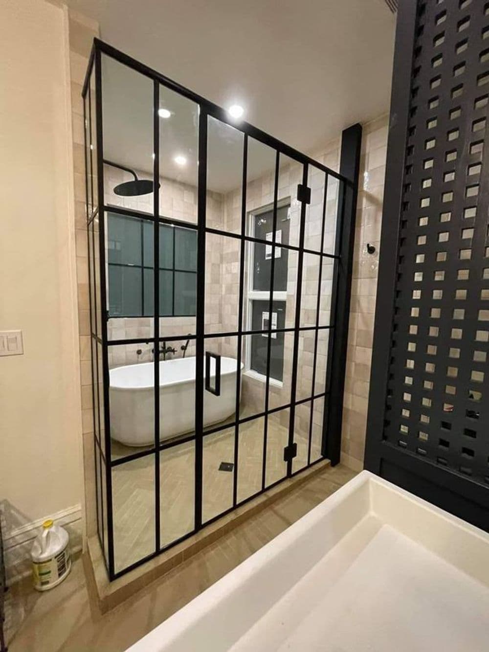 Modern bathroom featuring a black-framed shower enclosure and freestanding bathtub.