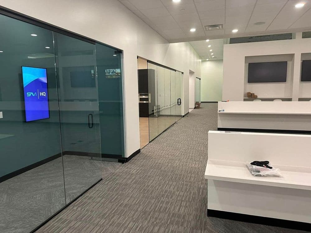 Modern office interior featuring glass meeting rooms and sleek workstations.